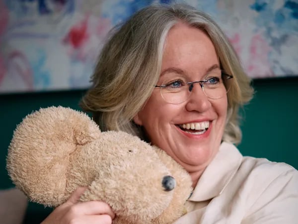 Gunda Frey lächelt und hält einen Teddybären, Thema Selbstannahme statt Heilungsdruck
