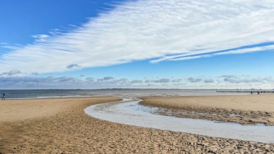 Weiter Strand mit offenem Horizont unter großem Himmel