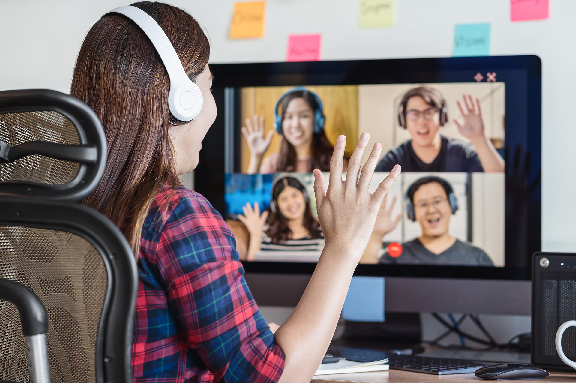 Frau sitzt an ihrem Schreibtisch und nimmt an einem Online-Seminar teil