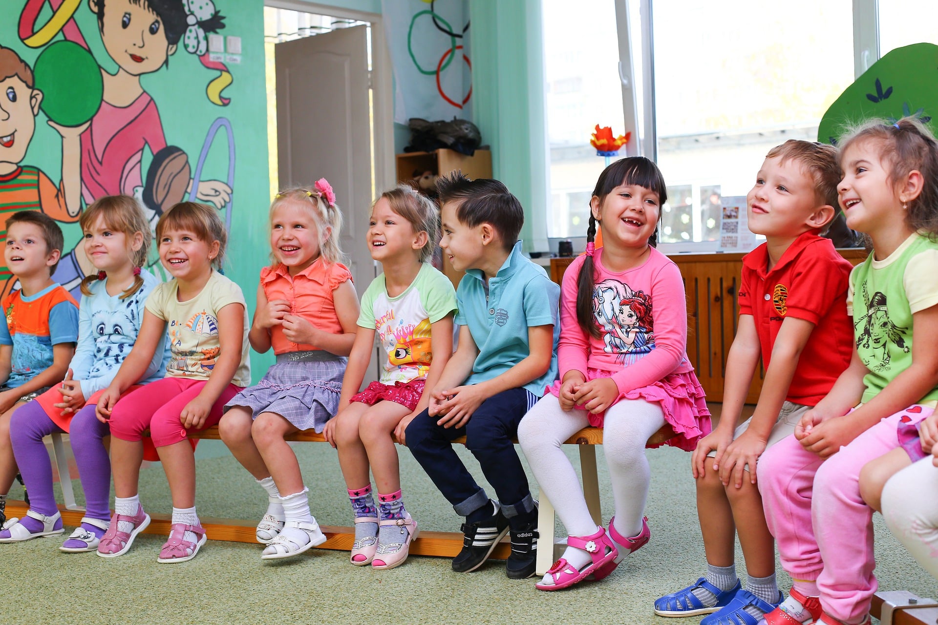 Kindergartenkinder sitzen auf einer Bank und Lachen